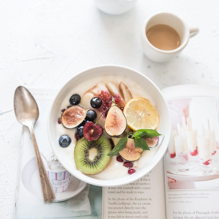 Ernährung als Ressource Frühstückstisch mit einer Schüssel Obst, Joghurt und einer Tasse Kaffee.