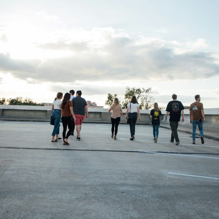 Titelbild zu Privatpersonen & junge Erwachsene Eine Gruppe von Personen läuft auf einer Dachterrasse in den Sonnenuntergang.